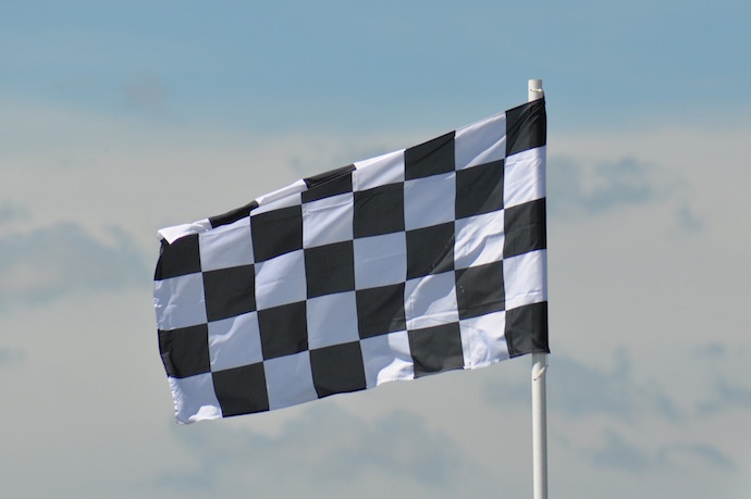 Photo of a chequered flag against a cloudy sky