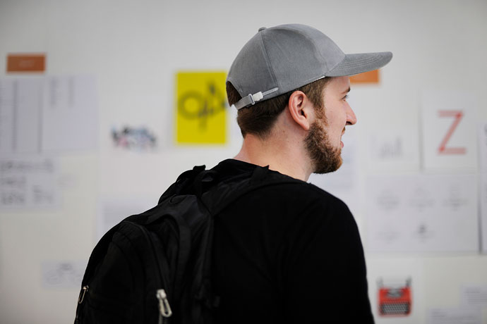 A young man wearing a black t-shirt and grey baseball cap