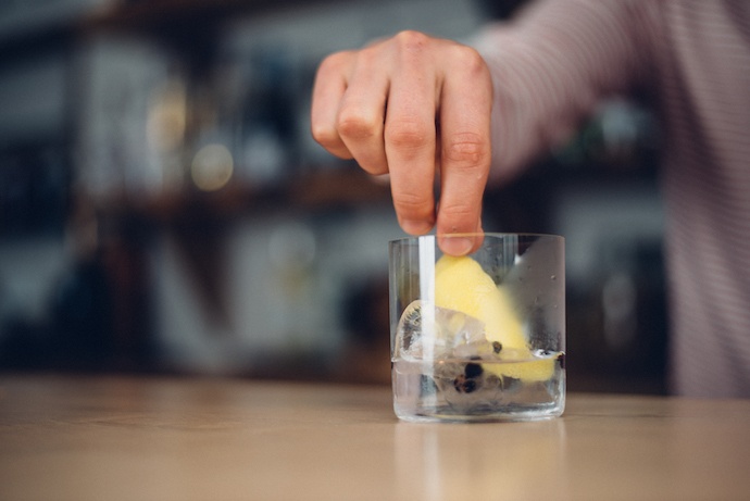 Photo of bartender placing a wedge of lemon into a drink