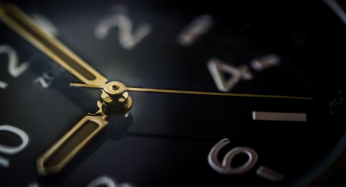 Close up of black clock face with brass hands.